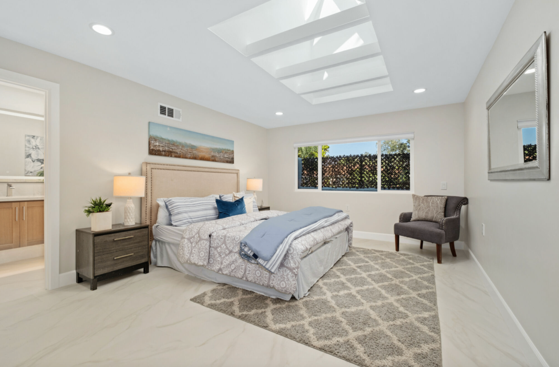 Bright primary bedroom with vaulted ceiling, skylights, and ensuite bath access